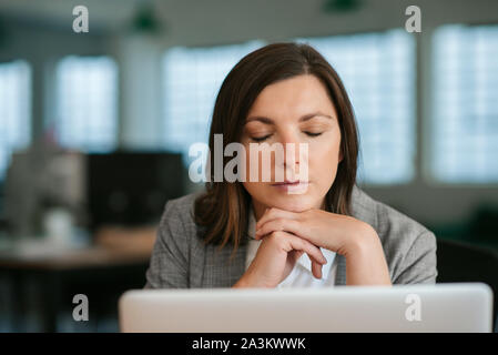 Müde businsswoman Sitzen mit geschlossenen Augen an ihrem Schreibtisch Stockfoto