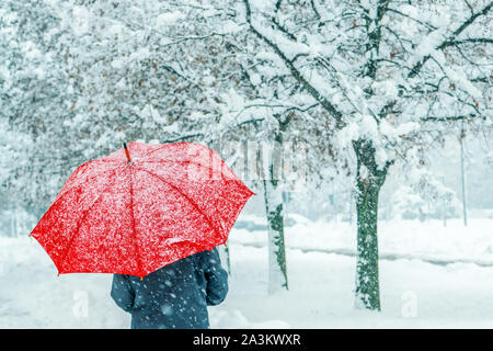 Frau unter roten Regenschirm im Schnee genießen Der erste Schnee der Wintersaison Stockfoto