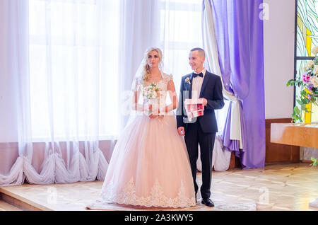 Braut und Bräutigam am Hochzeitstag zu Fuß im Freien auf Frühling Natur. Brautpaar, gerne frisch verheiratete Frau und Mann umarmen im Green Park. Liebe Hochzeit Stockfoto
