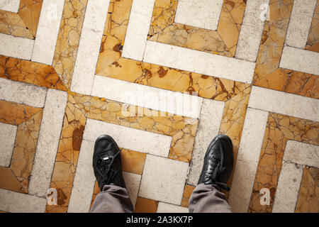 Männliche Füße in glänzend schwarz Leder Schuhe stehen auf Mosaik Stein, erste Person anzeigen Stockfoto