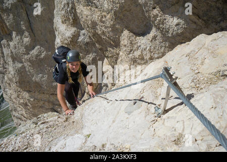 Attraktive Blondine weiblichen Bergsteiger auf einem steilen Klettersteig in Südtirol Stockfoto