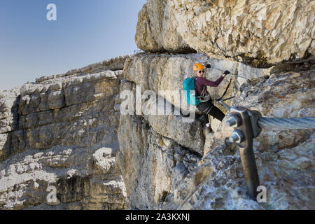 Attraktive Blondine weiblichen Bergsteiger auf einem steilen Klettersteig über Cortina d'Ampezzo Stockfoto