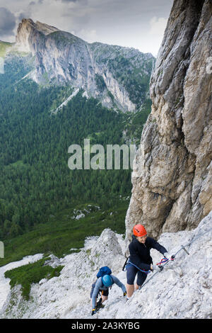 Ein Mann und eine Frau in den Zwanzigern Erklimmen einer steilen Klettersteig für Spaß im Urlaub Stockfoto