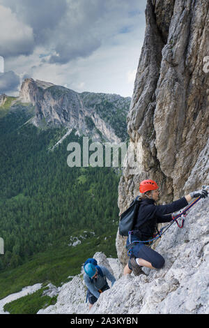 Ein Mann und eine Frau in den Zwanzigern Erklimmen einer steilen Klettersteig für Spaß im Urlaub Stockfoto