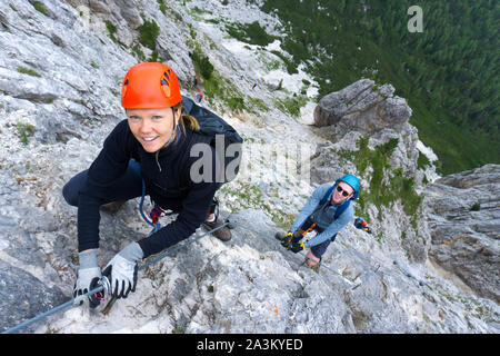 Ein Mann und eine Frau in den Zwanzigern Erklimmen einer steilen Klettersteig für Spaß im Urlaub Stockfoto