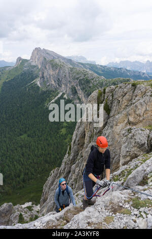 Ein Mann und eine Frau in den Zwanzigern Erklimmen einer steilen Klettersteig für Spaß im Urlaub Stockfoto