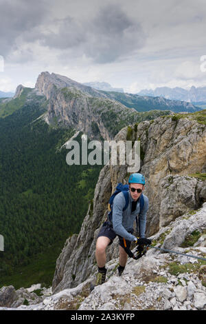 Ein Mann in den zwanziger Jahren an einem steilen Klettersteige in den Dolomiten von Alta Badia Stockfoto