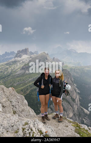 Zwei attraktive junge weibliche Bergsteiger auf dem Berggipfel und lächelnd Stockfoto