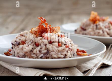 Risotto mit rotem Radicchio und knusprigem Speck (Speck) Nahaufnahme Stockfoto