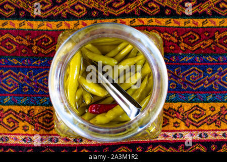 Istanbul, Türkei: Middle Eastern Food und Lifestyle, ein Glas Würzige grüne Chilis und Paprika auf einem Damast-tischdecke Stockfoto