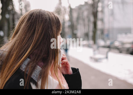 Junge Frau trägt warme Kleidung auf der Straße im Winter Stockfoto