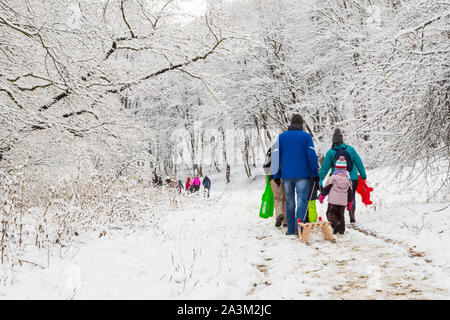 Menschen Eltern und Kinder auf Waldweg ziehen Schlitten zwischen Bäumen im Schnee im Winter, Tolvaj-arok, in der Nähe von Sopron, Ungarn Stockfoto