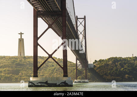 Spektakuläre Aussicht vom 25. April Hängebrücke über den Fluss Tejo und die Cristo Rei (Christus König) Denkmal bei Sonnenuntergang in Lissabon, Reise und Tourismus conc Stockfoto