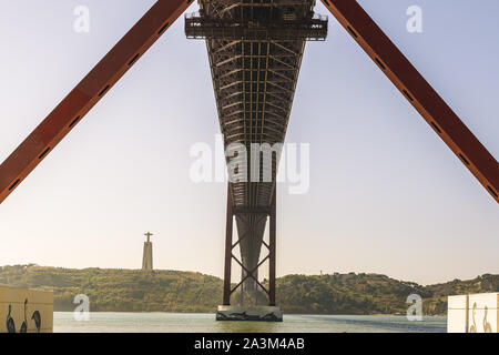 Symmetrische Ansicht des 25. April Hängebrücke über den Tejo von unten aus gesehen, auf der anderen Seite ist das Denkmal Cristo Rei (Christus König) Stockfoto