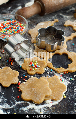 Cooking cookies mit blume Ausstecher auf einen dunklen Tisch Stockfoto