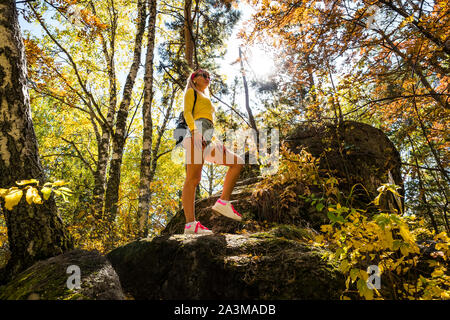 Stilvolle Frau in den Wald. Eine junge schöne Mädchen steht auf einem Stein vor dem Hintergrund einer goldgelben Blätter und Birken. Stockfoto