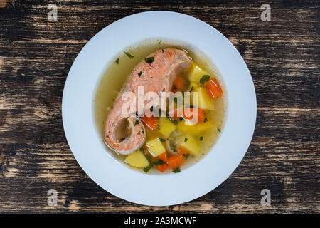 Frischer Lachs Fischsuppe mit Möhren, Kartoffeln und Kräuter in eine weiße Platte, aus der Nähe. Leckeres Abendessen besteht aus einer Fischsuppe mit Lachs Stockfoto