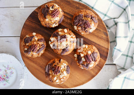 Frisch gebackene Banane Haferflocken Pecan und Schokolade Muffins auf Holzplatte Schuß in natürlichem Licht in flache Komposition legen. Gesunde und nahrhafte Zwischenmahlzeit. Stockfoto