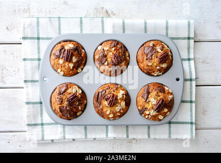 Frisch gebackene Banane Haferflocken Pecan und Schokolade muffins Muffin tin in flache Komposition legen. Gesunde und nahrhafte Zwischenmahlzeit. Stockfoto