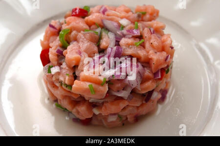 Lachs Fisch ceviche kochen servieren in einem Ring schließen bis auf weiße Platte Hintergrund. Selektive Weichzeichner. Traditionelle peruanische Küche Teller Konzept Stockfoto