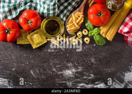 Italienische Pasta und Zutaten. Ravioli, Nudeln, Spaghetti, Tortellini, Tomaten und Basilikum Stockfoto