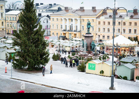 Helsinki, Finnland, 19.12.2018: Weihnachtsmarkt mit Weihnachtsbaum auf den Senatsplatz mit Schnee bedeckt. Urlaub Karussell und Menschen zu Fuß. Stockfoto