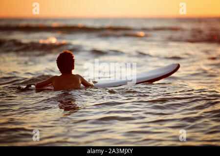 Junger Mann, Wave bei Sonnenuntergang. Einen aktiven Lebensstil. Surfen bei Sonnenuntergang Stockfoto