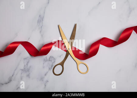 Grand opening Hintergrund. Gold Schere mit roter Schleife auf einem Marmor Hintergrund Stockfoto