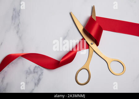 Grand opening Hintergrund. Gold Schere mit roter Schleife auf einem Marmor Hintergrund Stockfoto