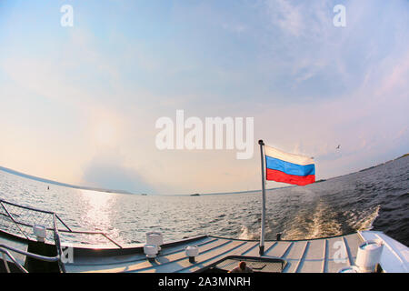 Russische Fahne im Wind auf dem Hintergrund von Wasser und Himmel. Stockfoto