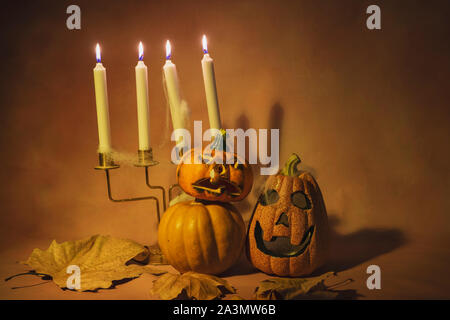 Spooky abend Halloween Kürbisse mit Kerze Kerzenständer auf orangefarbenem Hintergrund Stockfoto