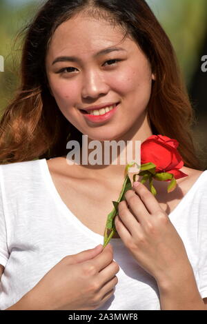 Hübsche Frau lächelnd mit einer Rose Stockfoto