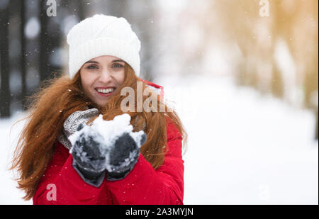 Glückliche junge Frau mit Schnee in den Händen Stockfoto