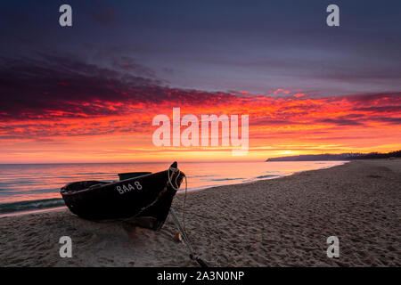 Traditionelle schwarze Farbe Fischerboot auf Sandstrand in Baabe, die Fischer in den Morgen mit orange Sunrise, Insel Rügen, Ostsee, Deutschland. Stockfoto