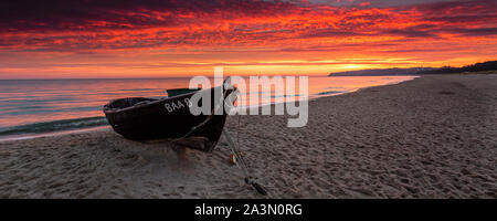 Traditionelle schwarze Farbe Fischerboot auf Sandstrand in Baabe, die Fischer in den Morgen mit orange Sunrise, Insel Rügen, Ostsee, Deutschland. Stockfoto