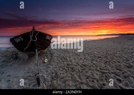 Traditionelle schwarze Farbe Fischerboot auf Sandstrand in Baabe, die Fischer in den Morgen mit orange Sunrise, Insel Rügen, Ostsee, Deutschland. Stockfoto