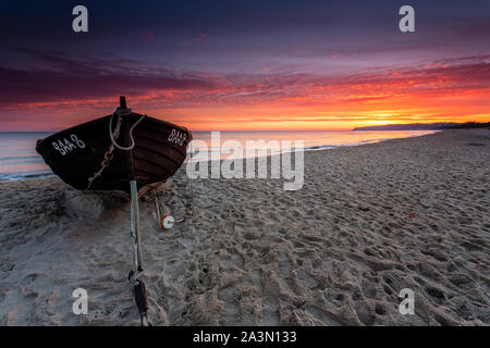 Traditionelle schwarze Farbe Fischerboot auf Sandstrand in Baabe, die Fischer in den Morgen mit orange Sunrise, Insel Rügen, Ostsee, Deutschland. Stockfoto