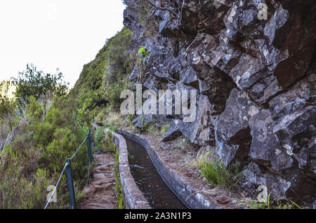 Levada 25 Fontes auf der Insel Madeira, Portugal. Das Bewässerungssystem Canal, Wanderweg, grünen Bäumen und Felsen. Beliebte Touristenattraktion, Wanderziele. Portugiesische Landschaft. Trekking. Stockfoto