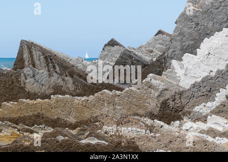 Yacht segeln Vergangenheit dramatische sedimentären Gesteinen - Flysch - Itzurun Strand, La Ravoire, Gipuzkoa, Baskisch Geopark, Spanien Stockfoto