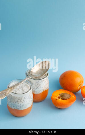 Diätetische Desserts mit zertrümmerte Aprikose und Chia Pudding auf blauem Hintergrund. Kopieren Sie Platz. Gesundes Frühstück Konzept. Vertikal Stockfoto