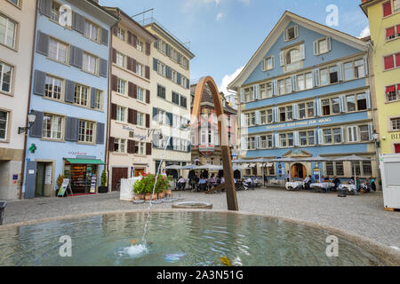 Straße Münsterhof in der Altstadt von Zürich mit öffentlichem Brunnen, Restaurants mit Außenterrassen und bunten Gebäuden Stockfoto