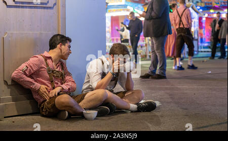 München, Deutschland - 24. September: 2 betrunken männlichen Besucher sitzen auf dem Boden und Essen eine Suppe auf dem Oktoberfest. Stockfoto