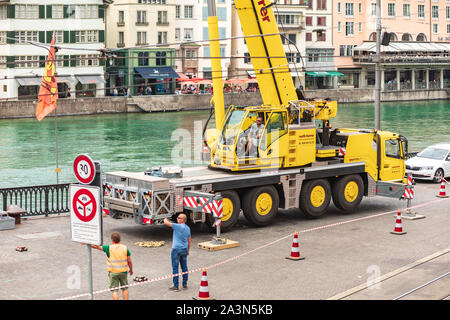 Arbeiter mit einem Kran in einem Bereich, der von Warnschildern umgeben ist, die Straßenarbeiten in der Limmatquai-Straße in der Nähe des Flusses Limmat in der Züricher Schweiz ausführen Stockfoto