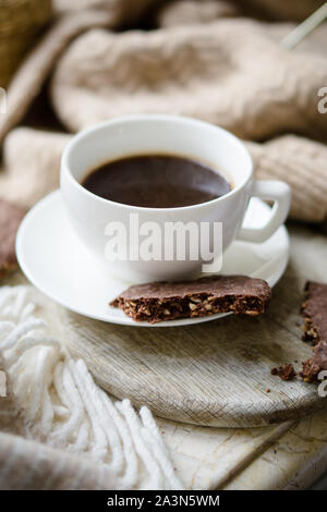 Tasse Kaffee mit Milch und Schokolade Cookies auf warme Wolldecke Stockfoto