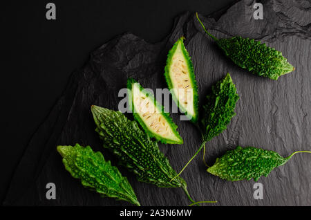 Bitter Gurke auf schwarzem Schiefer Hintergrund. Exotische Küche Konzept. Kopieren Sie Raum, flach Stockfoto