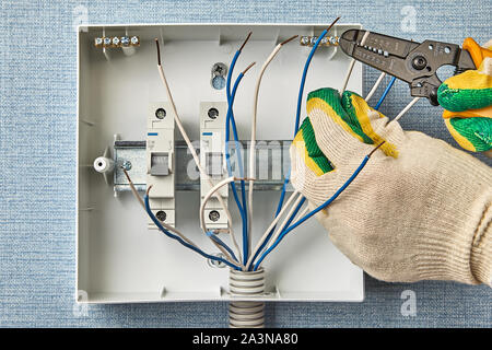 Ein Elektriker verwendet eine abisolierzange Isolierung ohne Schneiden von Kupfer zu entfernen. Installation einer elektrischen Panel mit Leistungsschalter. U Stockfoto