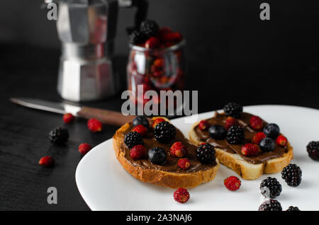 Leckere süße Toast mit frischen Beeren und Kaffee zum Frühstück auf dunklem Hintergrund. Stockfoto