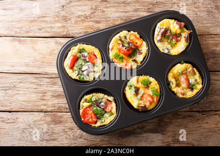Frittata in Form von Ei Muffins mit Gemüse, Käse, Speck und Pilzen close-up in einer Auflaufform auf den Tisch. Horizontal oben Blick von abov Stockfoto