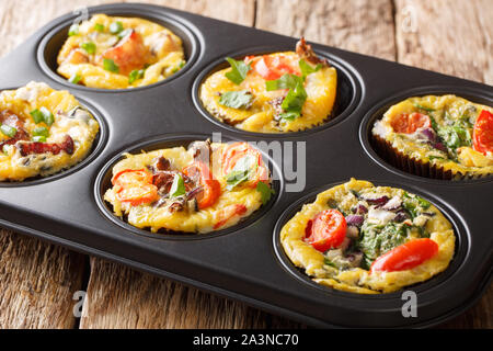 Frittata in Form von Ei Muffins mit Gemüse, Käse, Speck und Pilzen close-up in einer Auflaufform auf den Tisch. Horizontale Stockfoto