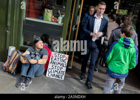 Ein Food science Demonstrant sitzt außerhalb einer McDonalds Restaurant in Whitehall während der Umweltschutz Protest über den Klimawandel Besetzung des Trafalgar Square in Central London, ist der dritte Tag der zwei Wochen anhaltenden weltweiten Protest von Mitgliedern des Aussterbens Rebellion, am 9. Oktober 2019, in London, England. Stockfoto